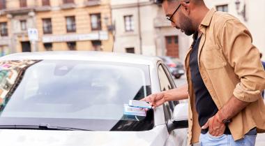 man scanning qr code on the front windscreen to rent a car